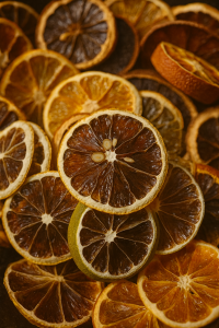 Close-up of dried orange, lemon, and lime slices layered in a pile, showing their translucent segments and golden-brown rinds.