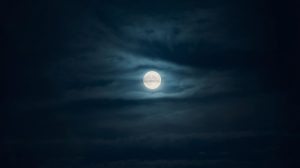 bright full moon in night sky with soft clouds