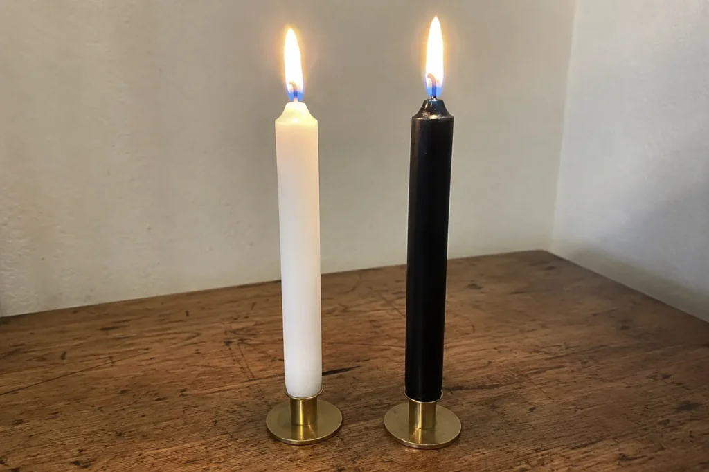 Black and white taper candles burning side by side for a Mabon balance ritual.