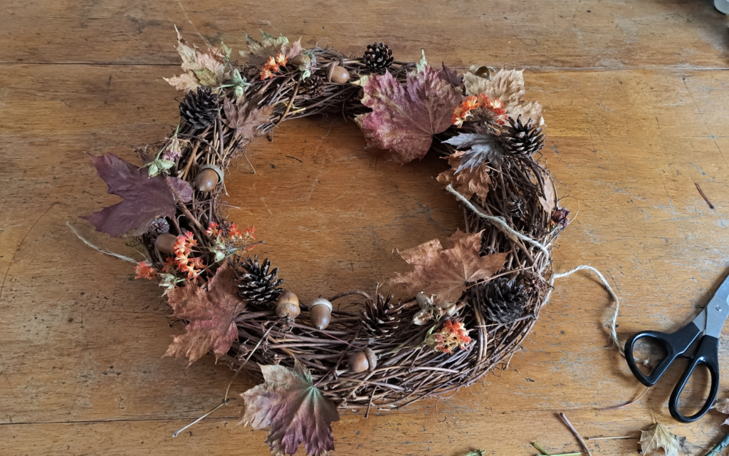 Finished Mabon harvest wreath made with dried leaves, pinecones, and seasonal herbs.