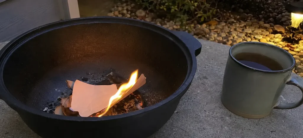 Handwritten release notes burning in a fire-safe cauldron beside a mug.